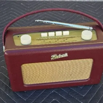 Vintage Roberts portable radio in a burgundy leatherette case with a carrying handle, telescoping antenna, and gold-tone grille.