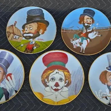 Set of five vintage Red Skelton collector plates with gold rims, featuring various clown characters painted by the comedian.