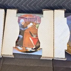 Three Norman Rockwell collector plates in their original cardboard packaging, featuring classic illustrated scenes.