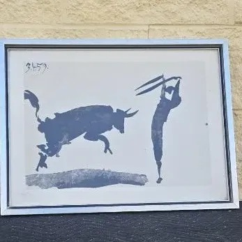 Framed Pablo Picasso lithograph print depicting a bullfight scene, housed in a simple silver-tone metal frame.