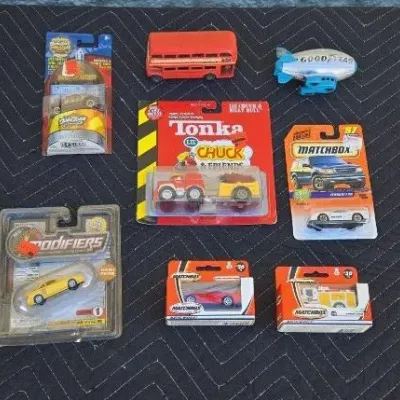 Collection of vintage toy vehicles, including carded Matchbox, Tonka, and Modifiers cars, alongside a loose red double-decker bus and a...