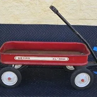 Vintage Sears XL-300 red metal toy wagon, showing some wear and rust consistent with age.