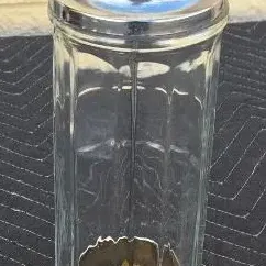 Vintage glass straw dispenser with a chrome lid and internal lift mechanism, showing some light wear.