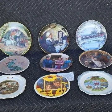 Collection of nine vintage decorative collector plates featuring various illustrated scenes, including historical, winter, and holiday...