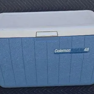 Vintage blue and white Coleman PolyLite 48 cooler, showing some light wear from use.