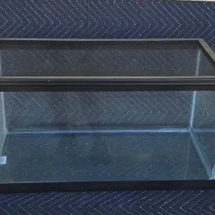 Glass terrarium or aquarium tank with a black mesh screen lid, in clean, used condition.