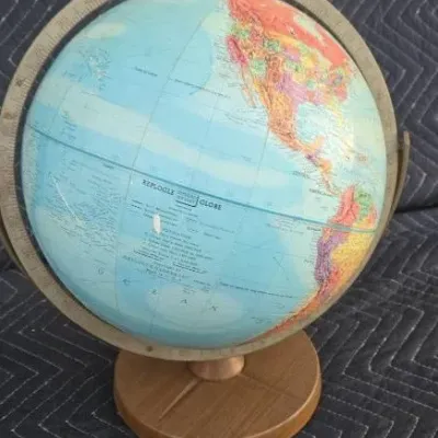 Vintage Replogle 12-inch world globe on a round wooden stand with a metal meridian ring.