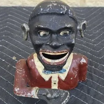 Vintage cast iron Jolly Nigger mechanical bank, showing significant paint wear and chipping consistent with age.