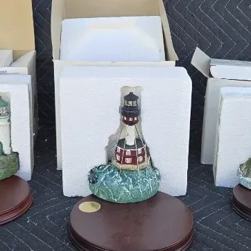 Three Harbour Lights collectible lighthouse figurines, each with its original box, styrofoam packaging, and wooden display base.