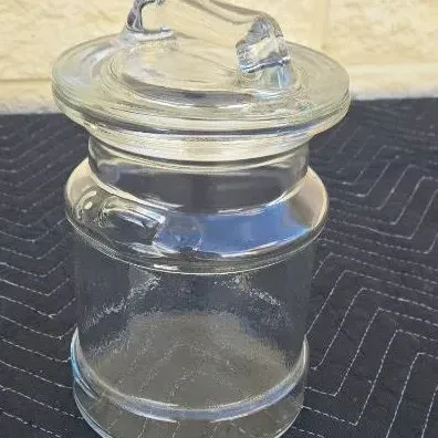 Vintage clear glass apothecary jar with a matching glass lid featuring a molded handle.