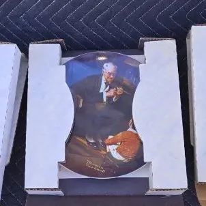 Three vintage Norman Rockwell collector plates, each housed in its original protective cardboard packaging.