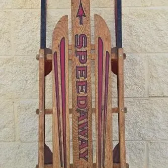 Vintage Speedaway wooden snow sled with metal runners and steering bar, showing some wear consistent with age.