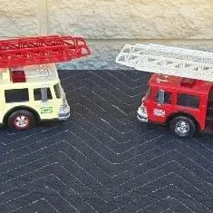 Two vintage Hess toy fire trucks with extending ladders, showing some light wear from play.