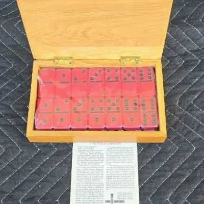 Vintage double-six dominoes set with red tiles, housed in a hinged wooden storage box with original instruction sheet.