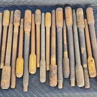 Collection of antique wooden vise screws and spindles, showing significant wear and patina from age and use.