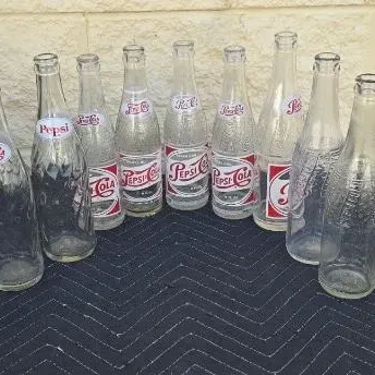Collection of vintage Pepsi-Cola glass bottles, featuring various red and white logo designs from different eras.