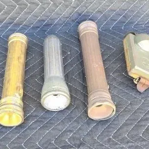 Collection of vintage flashlights, including three cylindrical metal models and one rectangular military-style elbow flashlight, showing...