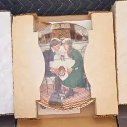 Three Norman Rockwell collector plates in their original cardboard packaging, featuring classic illustrated scenes.