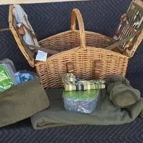 Vintage-style wicker picnic basket with double-hinged lids, complete with matching green fabric accessories, plates, utensils, and a...