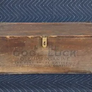 Vintage wooden crate repurposed into a hinged box, featuring faded stenciling for 'Good Luck Oleomargarine' on the front.