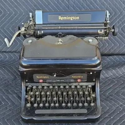 Vintage Remington Noiseless manual typewriter, featuring a black metal body, classic round keys, and gold lettering.