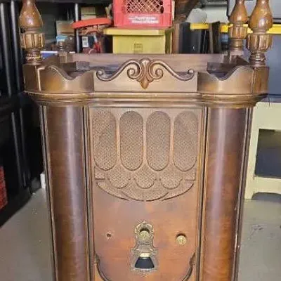 Vintage Philco console radio cabinet featuring ornate wood carvings, turned corner posts, and a decorative speaker grille, showing some...