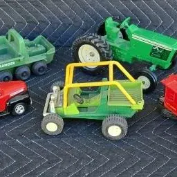 Collection of vintage toy vehicles, including a green John Deere tractor, a red pickup truck, a green and yellow dune buggy, a green...