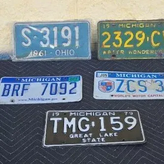 Collection of vintage license plates, including a 1961 Ohio plate and four Michigan plates from 1959, 1979, and later years, showing...