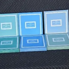 Three sets of boxed stationery or memory kits in shades of blue and teal, displayed open to show the interior lids.