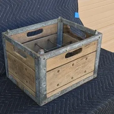 Vintage wooden milk crate with galvanized metal reinforcement, featuring built-in wire dividers and cut-out handles.