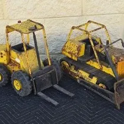 Pair of vintage Tonka pressed steel construction toys, including a forklift and a crawler tractor with bulldozer blade, showing...