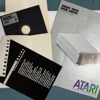 Sale Photo Thumbnail #6: Vintage Atari 1050 Disk Drive owner's guide, Atari BASIC reference guide, and a Master Diskette 3 floppy disk, circa 1980s.