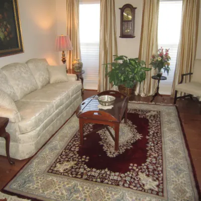 Traditional living room set featuring a cream damask upholstered sofa, a mahogany butler's tray coffee table, and a red and cream...