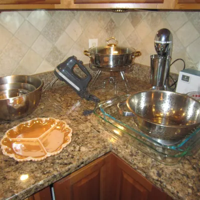 Assorted kitchenware including stainless steel mixing bowls, a hand mixer, a chafing dish, a milkshake maker, a colander, and a vintage...