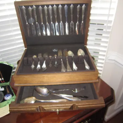 Vintage silver-plated flatware set housed in a two-tier wooden storage chest, shown alongside a small green Asian calligraphy set.