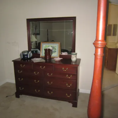 Traditional cherry wood double dresser with brass bail pulls and matching landscape mirror, featuring bracket feet and a multi-drawer...