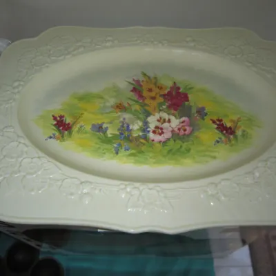 Vintage ceramic serving platter featuring an embossed floral border and a colorful painted wildflower scene in the center.