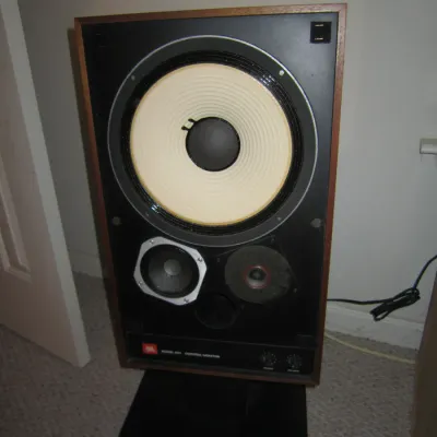 Vintage JBL Model 4311 Control Monitor speaker with a wood veneer cabinet, mounted on a black floor stand.