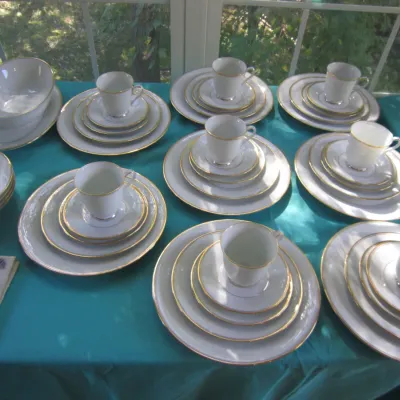 Lenox white porcelain dinnerware set with gold trim, including plates, saucers, teacups, and serving bowls.