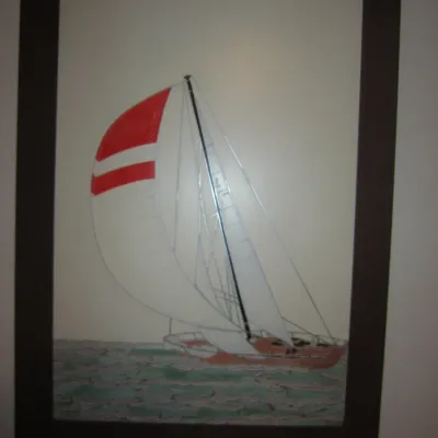 Framed vintage sailboat artwork featuring a red and white spinnaker sail, housed in a dark wood frame.