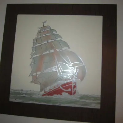 Vintage framed mirror art depicting a red-hulled sailing ship on choppy waters, featuring silvered details and a dark wood frame.