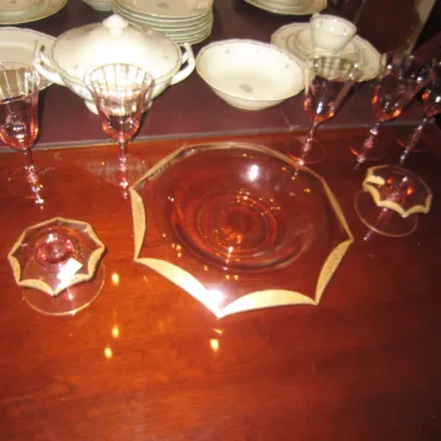 Vintage pink depression glass tableware set, including stemmed goblets, a large serving bowl with gold trim, and matching candlesticks,...