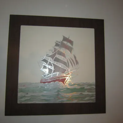 Vintage etched mirror wall art depicting a sailing ship on the water, housed in a dark wood frame.