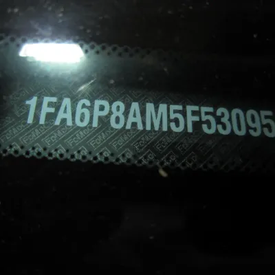 Vehicle Identification Number (VIN) plate visible through a car windshield.