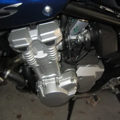 Close-up view of a Suzuki Bandit 1250S motorcycle engine, showing the clean silver-finished cylinder head and crankcase cover.