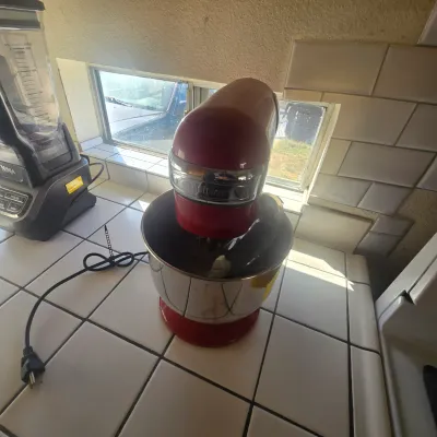 Red Cuisinart stand mixer with a stainless steel bowl, shown sitting on a tiled kitchen counter next to a Ninja blender, available for a...
