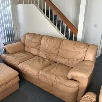 Vintage tan leather three-seater sofa showing moderate wear and creasing, available for a buy-it-now price of $150.
