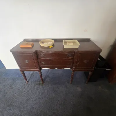 Antique dark wood sideboard buffet featuring two central drawers, two side cabinets, and fluted legs, showing some surface wear;...