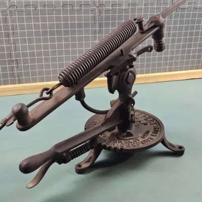 Antique cast iron cherry pitter, manufactured by the Rollman Manufacturing Company, featuring a spring-loaded mechanism and a circular...