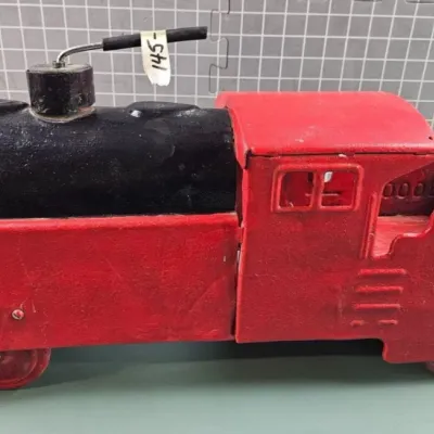Vintage cast iron toy locomotive, painted red and black, featuring the number 3000 embossed on the side.